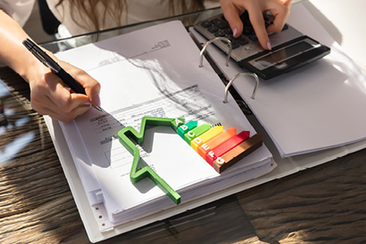 Ein lächelnder Mann telefoniert und hält ein Tablet in der Hand, während er an einem Laptop in einem modernen Büro sitzt.
